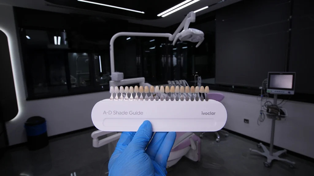 Dentist holding an A-D shade guide for selecting laminate veneer color in a modern dental clinic.