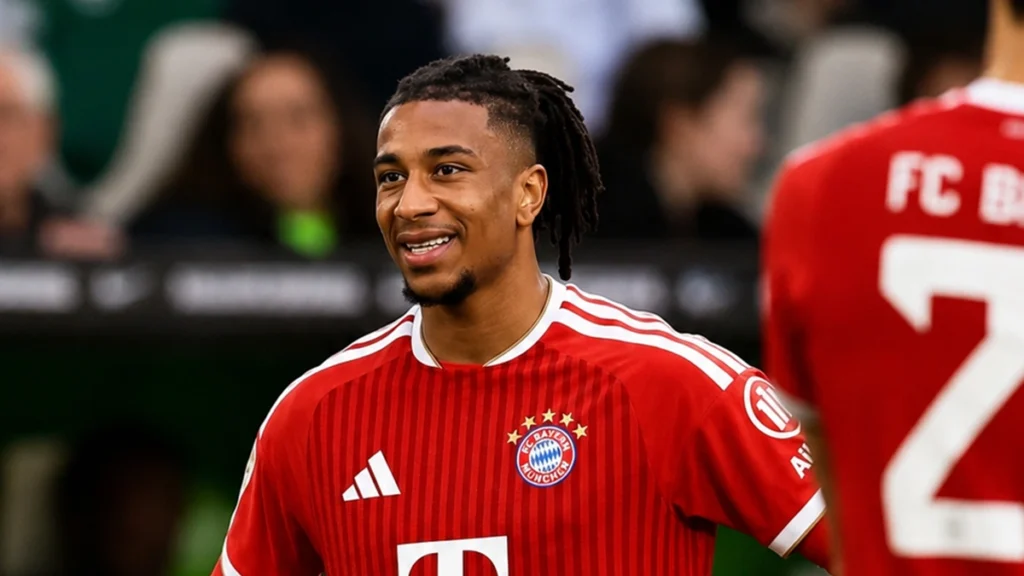 Michael Olise smiling in a Bayern Munich shirt during a football match