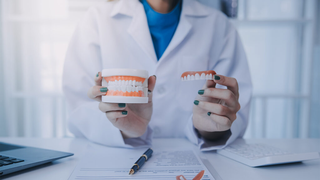 Sports dentist holding dental models while discussing preventive care and treatment options for professional athletes.