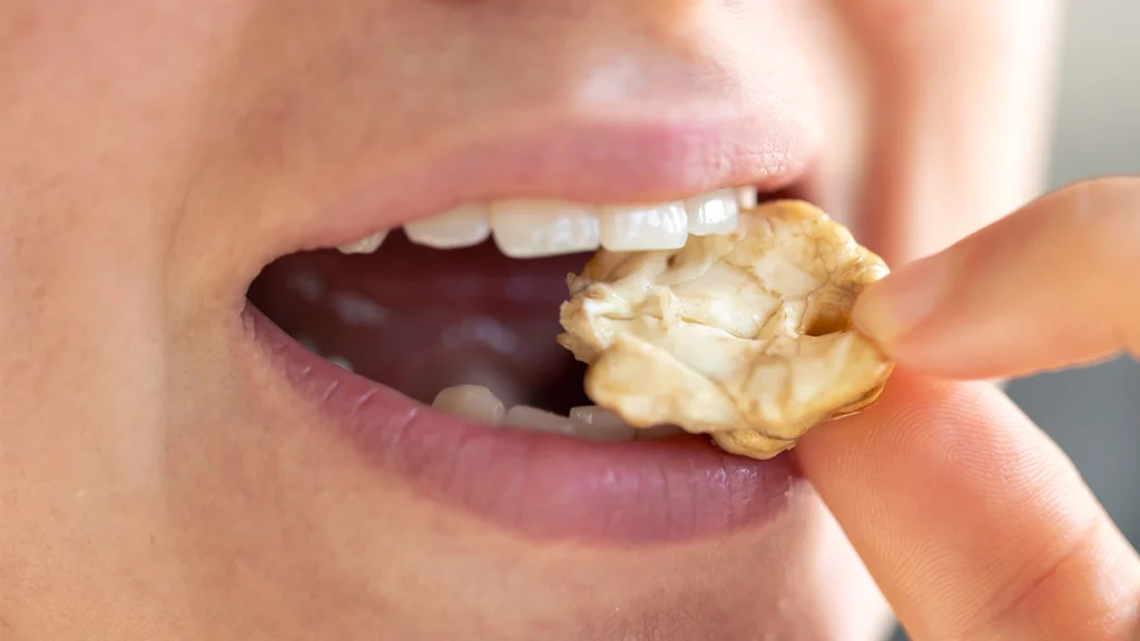Person biting a hard walnut, illustrating bite pressure and stress on dental crowns