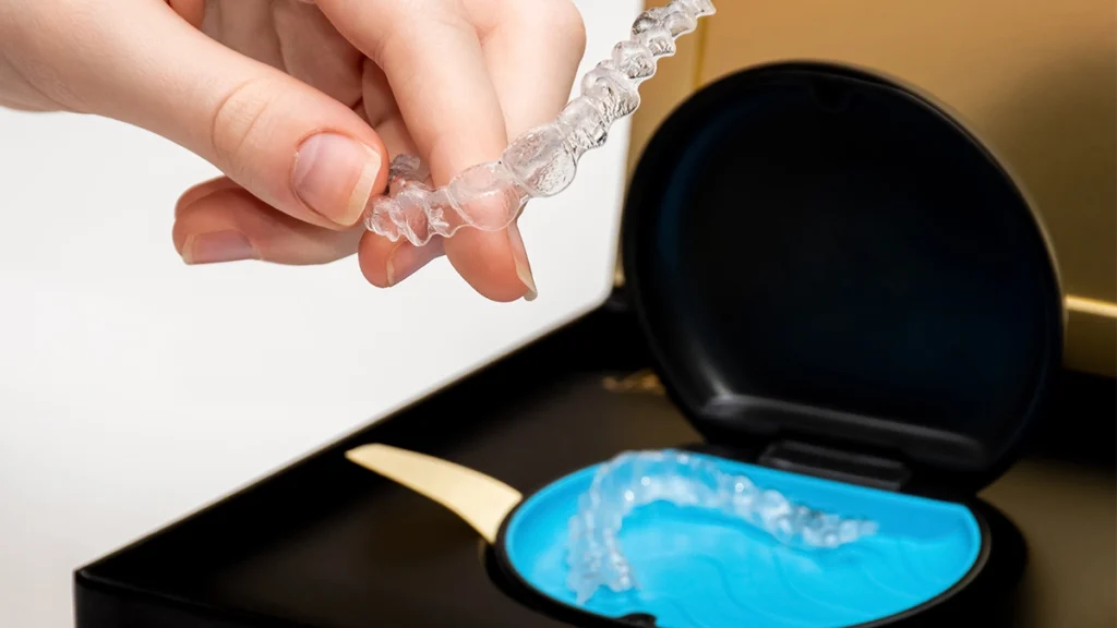 Invisalign clear aligner being held above an aligner case during orthodontic treatment