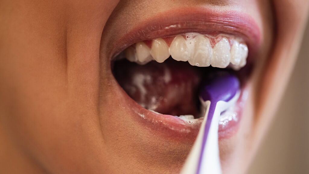 Close-up of an athlete brushing their teeth, highlighting daily oral hygiene and long-term dental health.