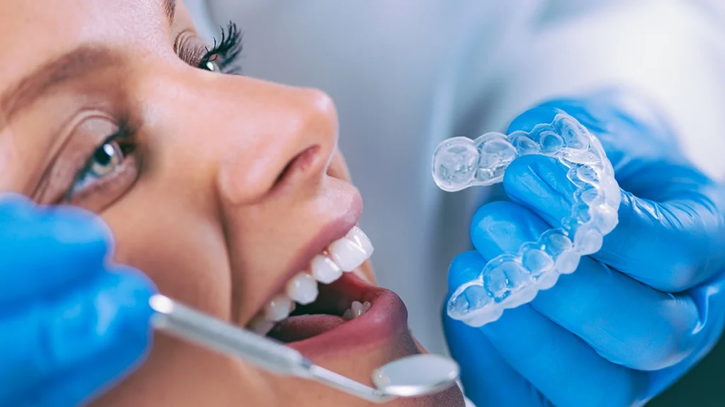 Dentist holding Invisalign clear aligners during patient consultation in Turkey