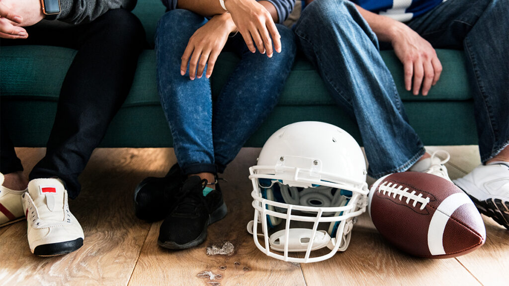 Football helmet and ball beside seated fans, representing NFL stars and the importance of healthy smiles.