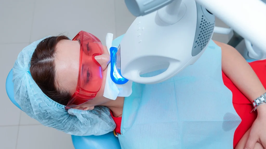 Patient receiving professional teeth whitening treatment with a dental whitening light
