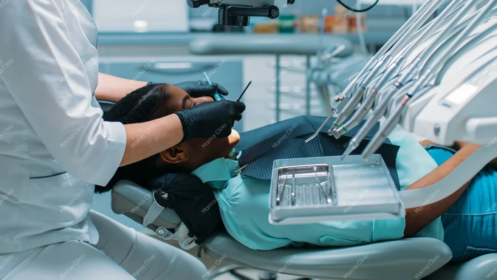 Dentist examining a patient in a dental clinic to assess oral health and suitable full mouth treatment options, including veneers, crowns, and dental implants.